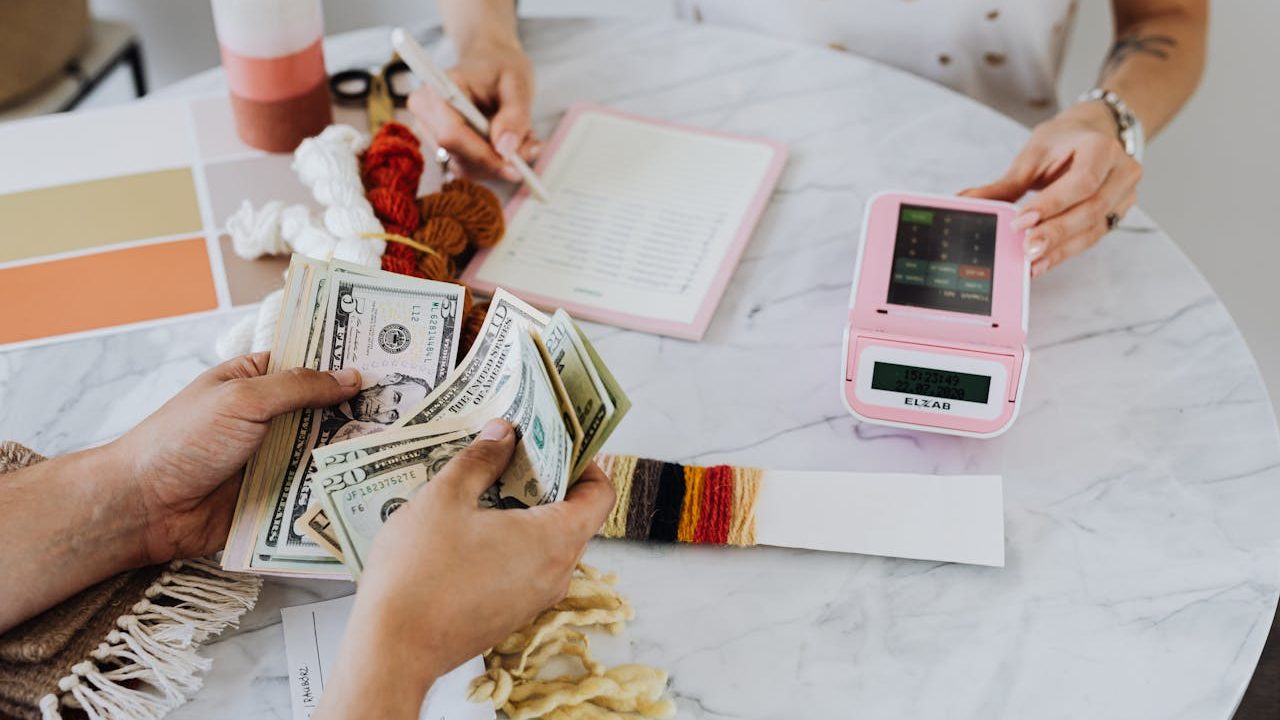 A hand holding US bank notes beside a card payment terminal on a counter — illustrating how the USAePay gateway connects card acceptance to a processor